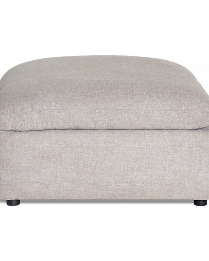 The My Cloud Slope 40 Ottoman showcases a beige upholstery with a cushioned top. Its simple, modern rectangular design and small black feet make it a comfortable, stylish addition to your customizable furniture collection.