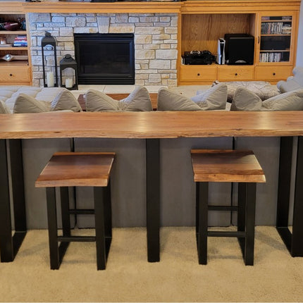 A wooden stool with a rectangular, dark wood seat and sleek black metal legs. The design is minimalistic and industrial, featuring clean lines and sturdy construction.