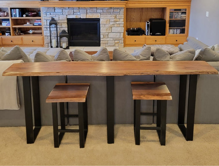 A wooden stool with a rectangular, dark wood seat and sleek black metal legs. The design is minimalistic and industrial, featuring clean lines and sturdy construction.