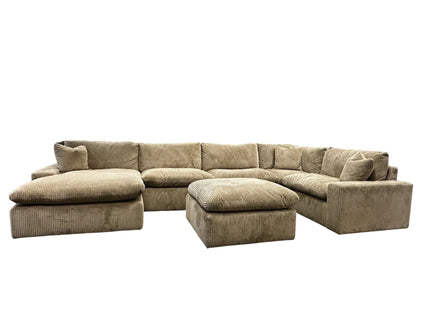 A large, plush gray sectional sofa with a matching ottoman is displayed in a showroom. A sign above reads, MY CLOUD: The Worlds Greatest & Most Comfortable Sofa. A bison image is in the background.