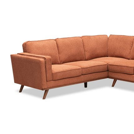 The Maddox LSF is a modern, L-shaped orange sofa featuring mid-century modern design. It has clean lines, plush cushions, wooden legs, and four back cushions for a sleek appearance. Ideal for contemporary interiors.