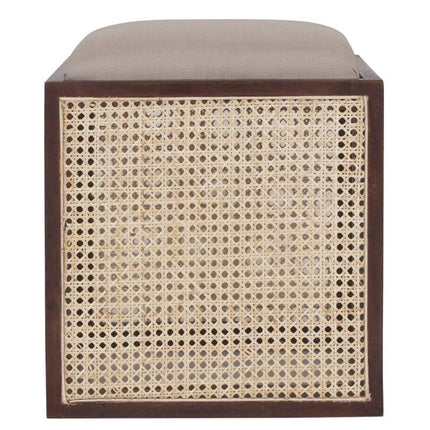 The Upholstered Stool With Cane features a dark wooden frame and a light brown cushion. Its sides are embellished with woven rattan, adding texture and style. This multifunctional handcrafted accent piece is perfect for any space.