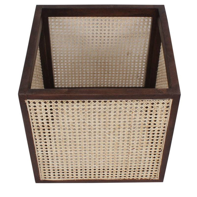 The Upholstered Stool With Cane features dark wooden edges and woven cane panels, serving as a handcrafted, multifunctional accent. The top-down view showcases the intricate weaving pattern of its panels.