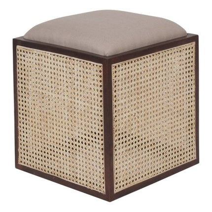 The Upholstered Stool With Cane boasts a beige cushion on a handcrafted dark wooden frame, with woven rattan sides, blending style and functionality as an accent piece.