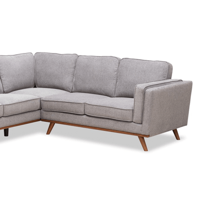 Discover the Maddox RSF: a stylish L-shaped gray sofa with wooden legs. Its plush cushions and squared armrests offer a mid-century modern vibe. With an angled design, it beautifully highlights its spacious seating area.