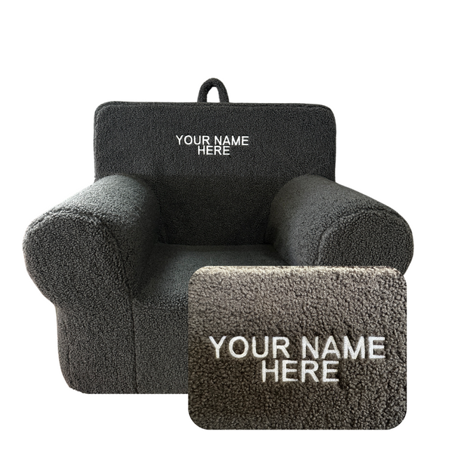 The My Cloud Kidz Chair is a dark gray, plush armchair with thick Sherpa upholstery and a customizable embroidery area on the backrest displaying Your Name Here. Its stylish rounded design combines with personalized options, featuring an inset for detailed embroidery.