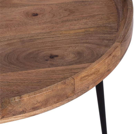 Introducing the Mango Bowl Coffee Table: a circular piece crafted from mango wood featuring a smooth surface and natural grain. This mid-century inspired table boasts a raised edge and is elegantly supported by slender black metal legs.