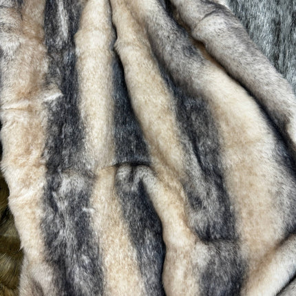 Close-up of the RCL Fur Throw, a soft and fluffy reversible blanket with a gradient striped pattern in beige, cream, and gray. Its warm and cozy texture features seamlessly blending shades for an ideal throw blanket experience.