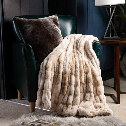 A dark green armchair, covered with a plush RCL Fur Throw, settles into a cozy room. A matching plush pillow sits on the chair. A lamp and side table are partially visible, enhancing the warm ambiance.