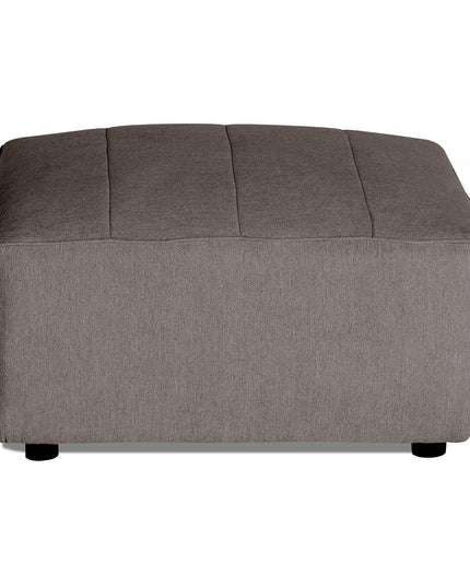 The Millenium Ottoman is a rectangular, gray piece with a modern luxury design, featuring subtle vertical stitching on top and black round feet. Its soft fabric texture complements modular sofa setups beautifully.