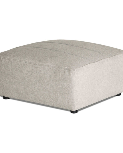 Discover the Millenium Ottoman: a large, square, light gray piece with a sleek fabric finish and subtle stitching. It stands elegantly on small black cylindrical legs, capturing modern luxury in every detail.