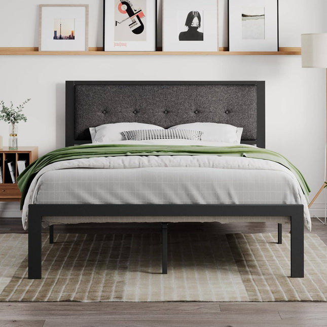 In a modern bedroom, the Modena Platform Bedframe + Headboard features prominently with a dark upholstered frame, neatly dressed in gray and white bedding and an olive green throw. Four framed artworks are displayed above. A wooden nightstand and a floor lamp sit on top of a striped rug.
