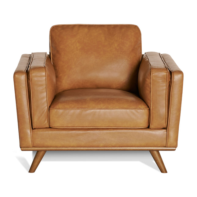 The Maddox Chair, a brown leather armchair with a mid-century modern boxy design, is centered in the image. It showcases plush cushions, wide armrests, a squared back, and tapered wooden legs on a plain white background.