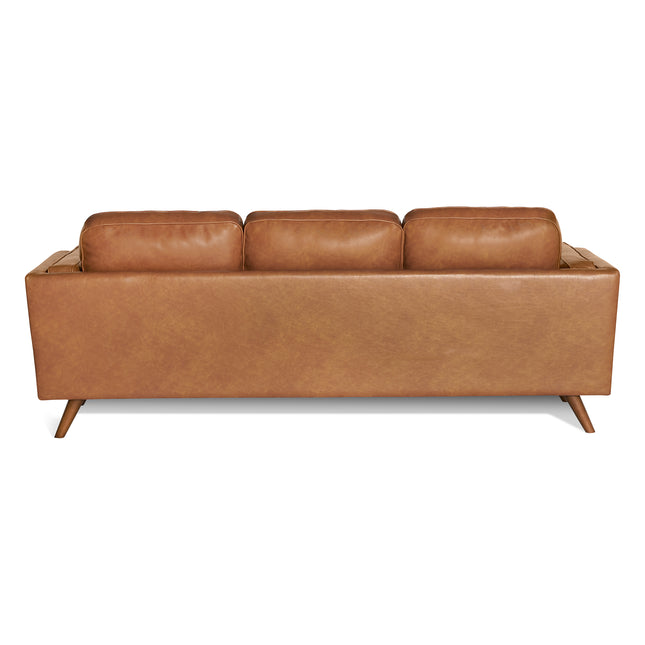 The Maddox Sofa is shown from the back, highlighting its modern brown leather design with three plush cushions and tapered wooden legs, all set against a crisp white background.