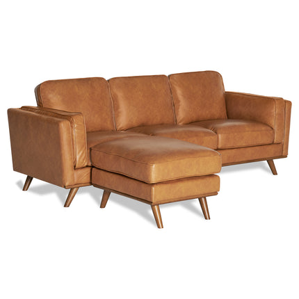 The Maddox Sofa is a brown leather sectional with plush cushions and a left-side chaise lounge. This mid-century modern design includes three cushioned backrests and wooden legs, set elegantly against a white background.
