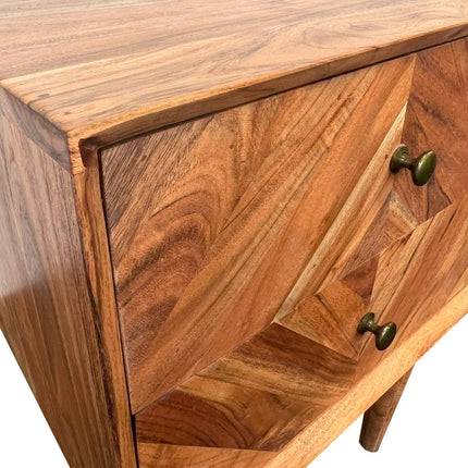 Close-up of the MCM Bedside Table, a mid-century nightstand with a chevron pattern. It has two drawers, each fitted with round dark metal handles. Made from solid mango wood, it highlights a natural grain in varying shades of brown.