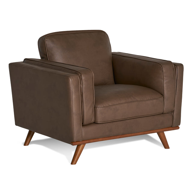 The Maddox Chair, with a mid-century modern design, features plush cushions, clean lines, padded armrests, and angled wooden legs in brown leather, set against a plain white background.