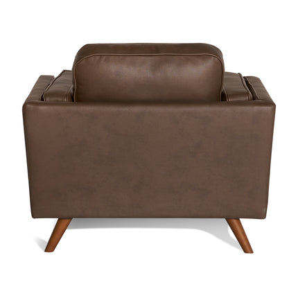 The back view of the Maddox Chair, a mid-century modern brown leather armchair, displays slightly angled wooden legs against a white background and features plush cushions on the backrest and armrests, reflecting its timeless design.