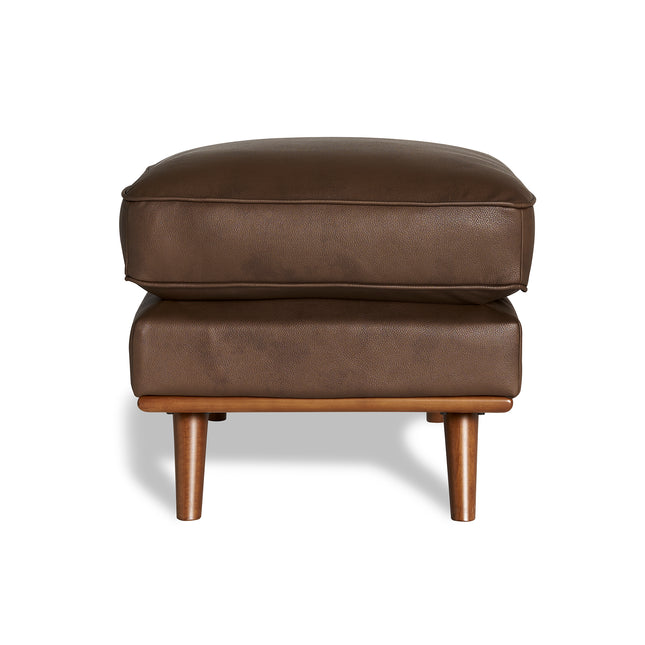 The Maddox Ottoman enhances your living space with its brown leather design, featuring two stacked cushions and four short wooden legs set against a crisp white background.
