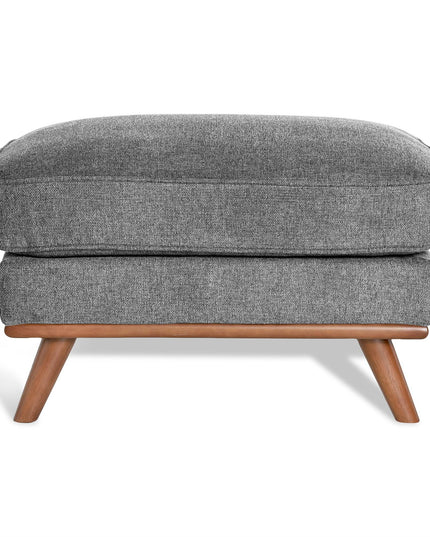 The Maddox Ottoman has a gray upholstered rectangular cushion with subtly textured fabric, supported by four angled wooden legs, adding mid-century charm to any living space.