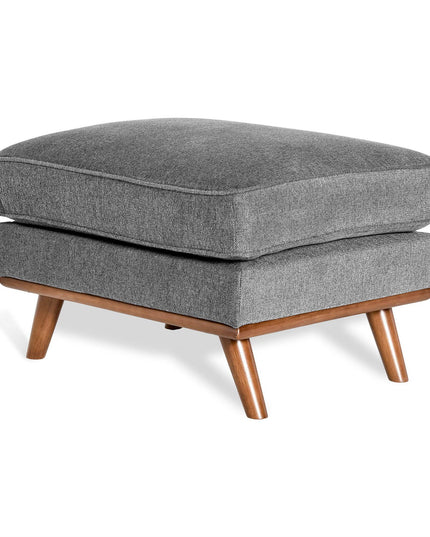 The Maddox Ottoman features a rectangular cushion in modern gray atop angled wooden legs with a light brown finish. Its simple mid-century contemporary design suits various living spaces.