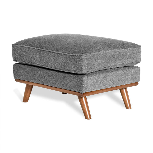 The Maddox Ottoman features a rectangular cushion in modern gray atop angled wooden legs with a light brown finish. Its simple mid-century contemporary design suits various living spaces.