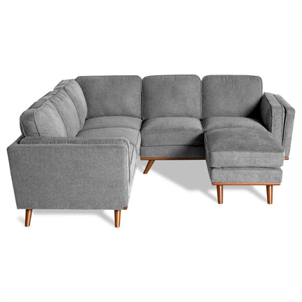 The Maddox Sectional is an L-shaped, gray sofa with wooden legs, cushioned backrest, and armrests. Its stylish mid-century modern design complements any living room when set against a plain white background.