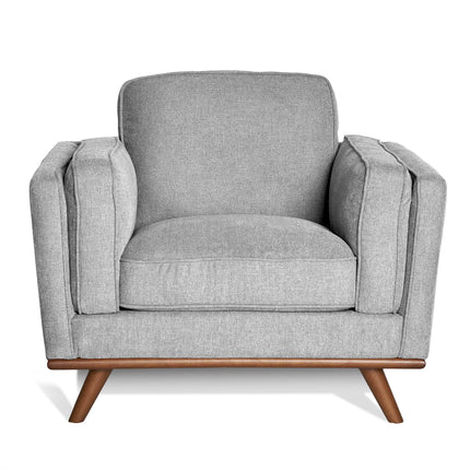 Discover the Maddox Chair, a mid-century modern masterpiece with a stylish boxy design. This gray armchair includes plush cushions, wooden legs, and thick armrests against a white backdrop for timeless appeal.