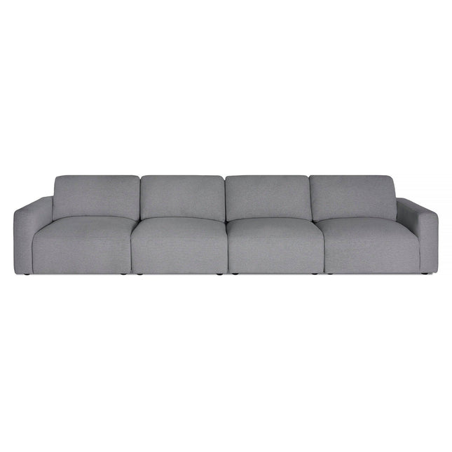 The Lugano Sectional is a large, light gray modular sofa with four connected seats and low armrests, blending Italian luxury and minimalist design. Its smooth cushions offer a modern look and plush comfort for ultimate relaxation.