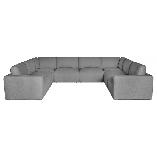 The Lugano Sectional is a gray, U-shaped sofa that epitomizes Italian luxury with its modern, minimalist design, featuring low backrests, plush cushions, and an even finish, ideal for contemporary living spaces.