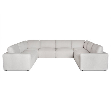 The Lugano 8 Piece Pit is a large, light gray L-shaped sectional sofa set against a white background. Made with premium materials, it showcases a modern design and features plush cushions with a low backrest, providing ample seating space.