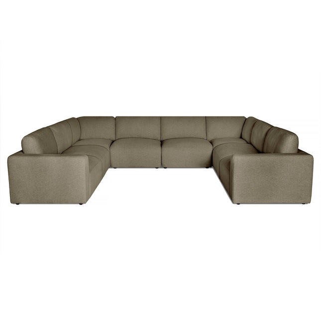 The Lugano sectional sofa showcases Italian luxury with modern design. Its large U-shaped layout in gray features plush cushions, low backrests, and wide armrests for comfort, ideal for multiple people against a plain white backdrop.