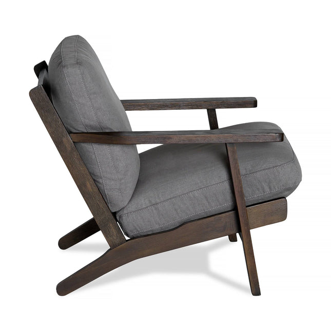 Side view of the Peyton Chair, featuring a stylish dark wooden frame and gray cushions. Its comfortable design includes an angled backrest and minimalist aesthetic, blending mid-century and contemporary styles seamlessly.