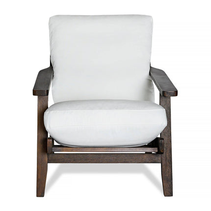 The Peyton Chair features a dark brown wooden frame, thick white cushions for the seat and backrest, and a mid-century style with clean lines and sturdy design for both style and comfort.