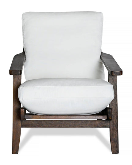 The Peyton Chair features a dark brown wooden frame, thick white cushions for the seat and backrest, and a mid-century style with clean lines and sturdy design for both style and comfort.