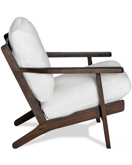 The Peyton Chair features a side view with a dark wooden frame and white cushions. Its mid-century modern design has sleek, angled legs that seamlessly blend minimalist aesthetics with comfort.