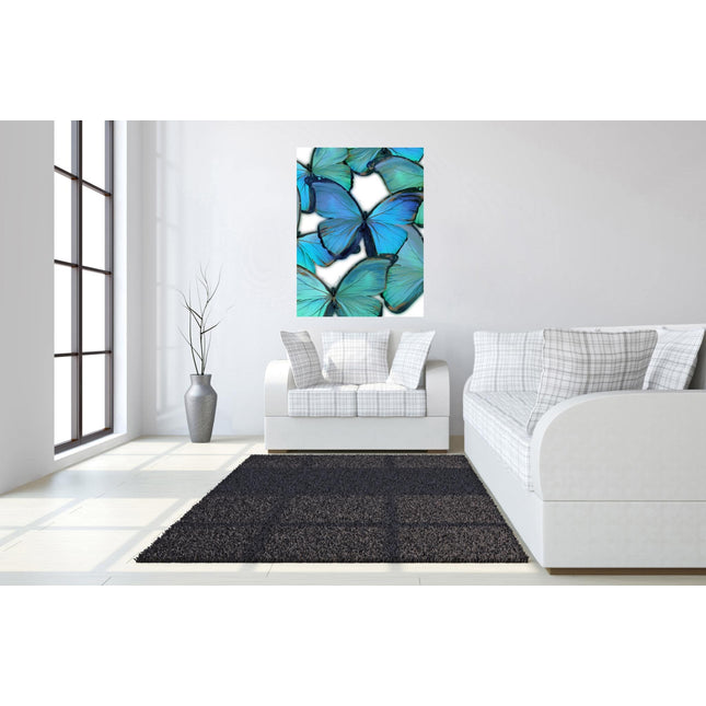 A modern living room with a white sofa, cushions, dark rug, and Butterfly museum-quality artwork featuring blue and green butterflies is beautifully illuminated by natural light through a tall window. A floor vase with twigs completes the decor, making it perfect for any home or office.