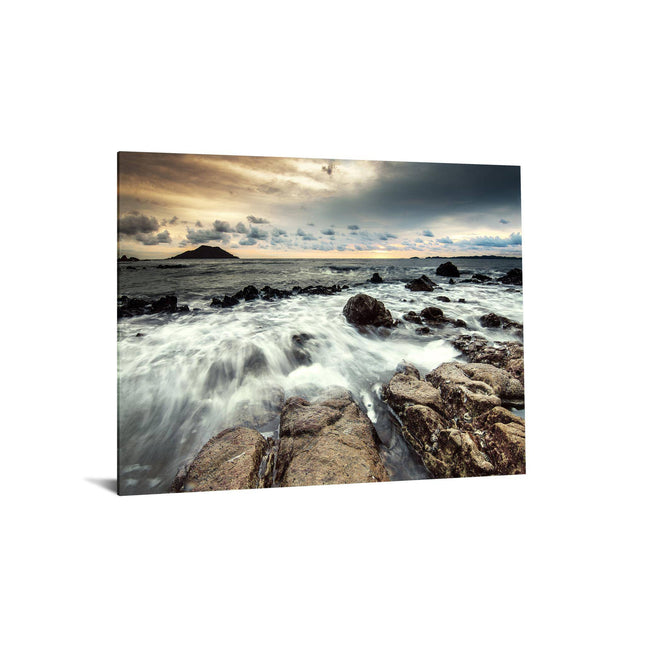 The Shoreline artwork captures a dramatic seascape with waves crashing over rocky shores under a moody sky. Distant hills line the horizon, showcasing the seas energy and dynamic natural beauty, reminiscent of museum-quality art.