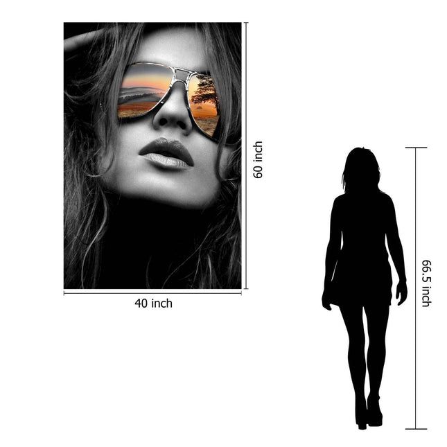 The 60x40 museum-quality artwork Reflective Shades is a black-and-white poster featuring a woman in sunglasses reflecting a sunset over water with trees. For size reference, its compared to a silhouette of a person who is 66.5 inches tall.