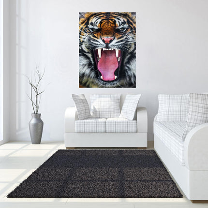 A modern living room showcases a white sofa with plaid pillows and a black rug. The Roaring Tiger, a museum-quality artwork, is displayed above the sofa. Natural light pours in through tall windows on the left, and a tall potted plant stands beside the sofa.
