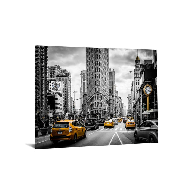 Under tempered glass, the NYC piece features a black and white city street with yellow taxis in color. The Flatiron Building stands prominently at the center amidst stunning historic and modern architecture.