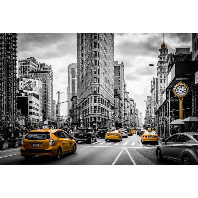 The NYC artwork depicts a lively city street with yellow taxis cruising by New Yorks iconic Flatiron Building. A flurry of cars and pedestrians evokes the feel of a museum piece in mostly black-and-white, highlighting only the taxis and a sidewalk clock in color.