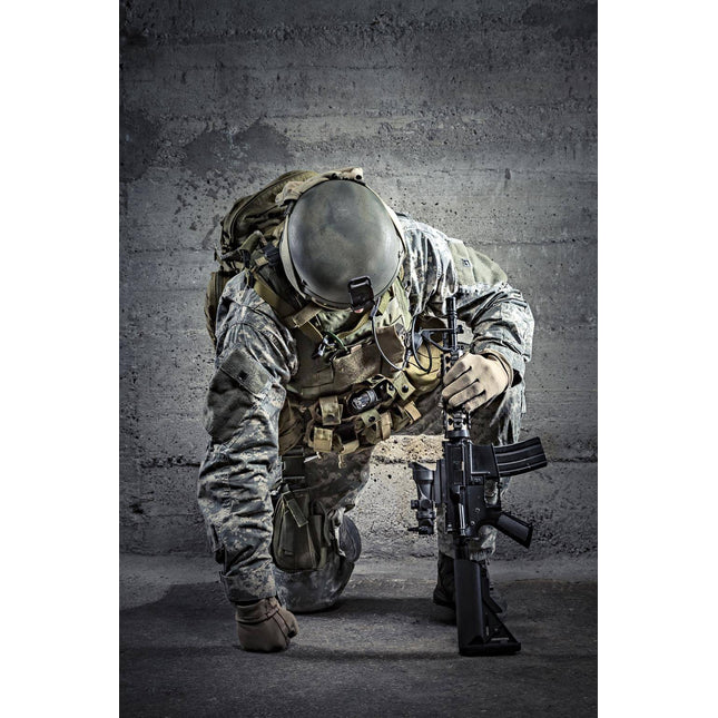 The Kneeling Soldier depicts a camouflaged soldier with one knee on the ground, holding a rifle vertically. Dressed in tactical gear and helmet, they are set against a textured concrete wall, with dramatic lighting that evokes museum-quality artwork.