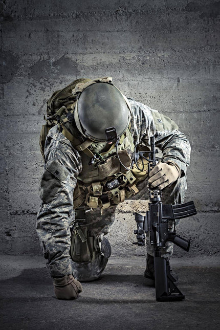 The Kneeling Soldier depicts a camouflaged soldier with one knee on the ground, holding a rifle vertically. Dressed in tactical gear and helmet, they are set against a textured concrete wall, with dramatic lighting that evokes museum-quality artwork.