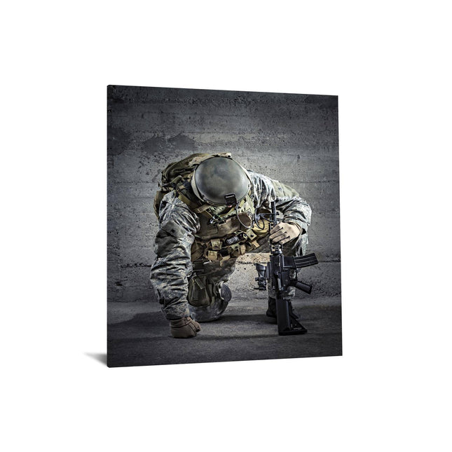 The Kneeling Soldier, clad in camouflage gear with a helmet and tactical vest, holds a rifle with both hands while kneeling against a textured concrete wall—perfect as museum-quality artwork for any home or office.