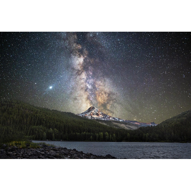 A stunning scene called Starry Mountain showcases the Milky Way galaxy stretching above a snow-capped peak, surrounded by dense forest. A tranquil, glass-like lake reflects the starry sky and lush greenery in the foreground.