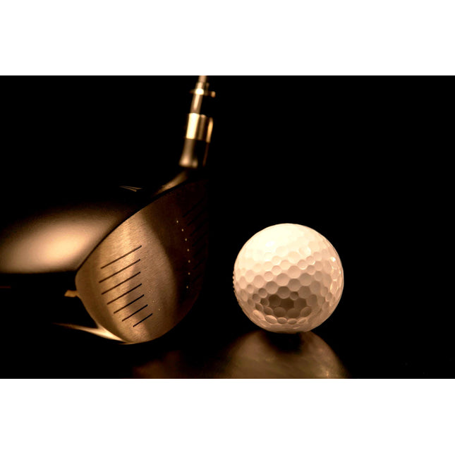A close-up of Golf Swing captures a golf club head and white ball against a dark backdrop. The metal grooves stand out, enhancing its texture. Ideal for home or office decor, this museum-quality image is encased in tempered glass.