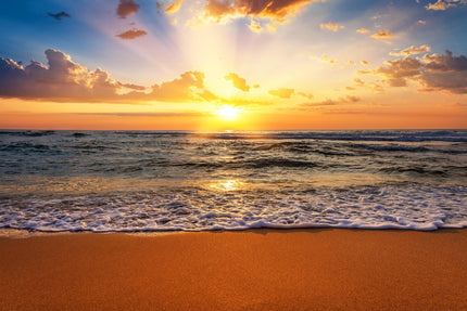 The Sunset Beach product features a vibrant ocean sunset with golden light streaming through clouds. The suns reflection on the water and gentle waves on the sandy shore create a serene ambiance, ideal for museum-quality artwork in your home or office.