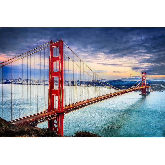 The image, titled Golden Gate, showcases San Franciscos iconic red suspension bridge at sunset. The bridge elegantly stretches over tranquil waters, set against a cloudy sky with the city skyline in the background, creating an art piece of museum quality.