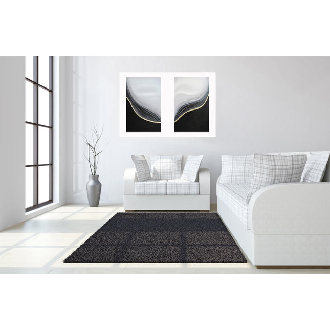 A modern living room features the Curve Set, comprising a sofa and chair with plaid cushions. A dark gray rug adorns the floor, while a hand-painted textured canvas adds charm above the furniture. A vase with branches sits beside the chair, completing the look against white walls.